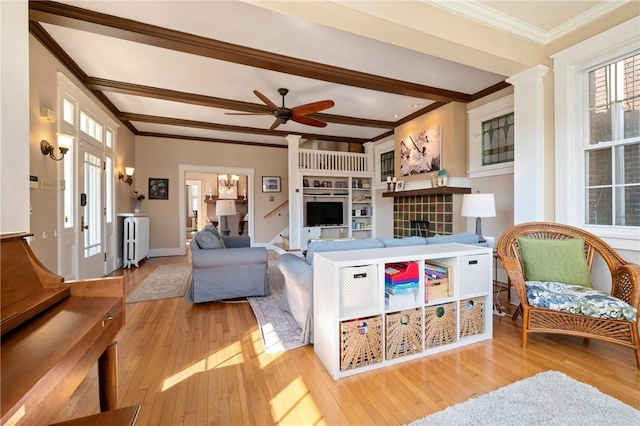 living area with beam ceiling, ornamental molding, a ceiling fan, hardwood / wood-style flooring, and decorative columns