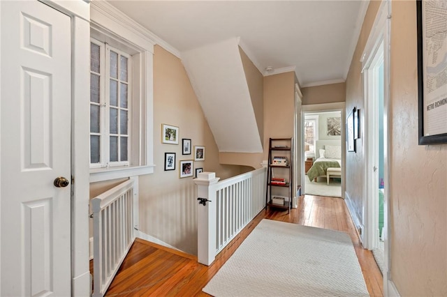 corridor featuring hardwood / wood-style flooring, an upstairs landing, crown molding, and baseboards