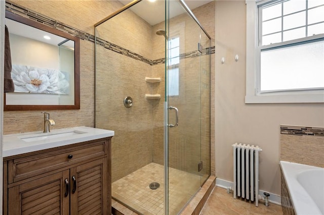 bathroom featuring a wealth of natural light, radiator, a stall shower, and a garden tub