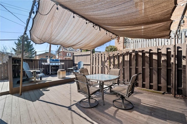 wooden terrace featuring outdoor dining space, fence, and grilling area