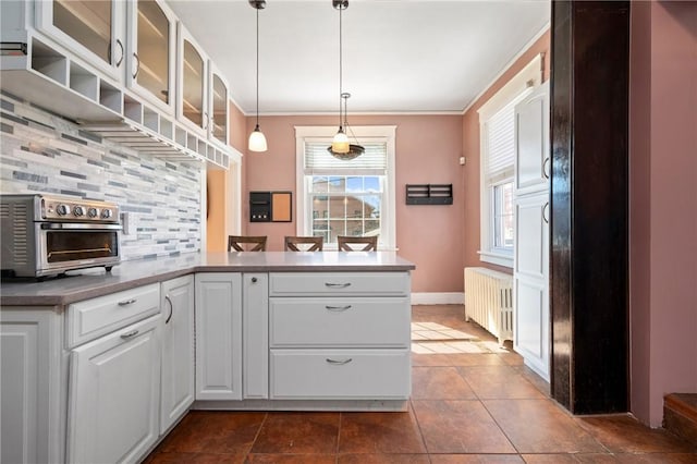 kitchen featuring a toaster, radiator heating unit, ornamental molding, white cabinets, and tasteful backsplash