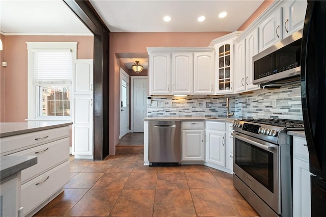 kitchen featuring recessed lighting, glass insert cabinets, appliances with stainless steel finishes, white cabinetry, and tasteful backsplash