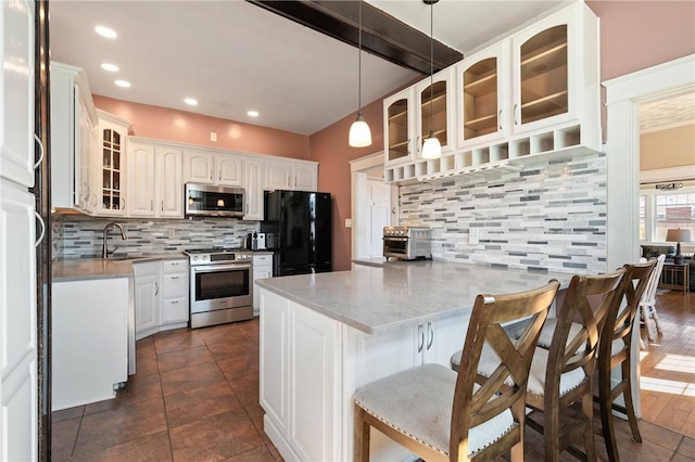 kitchen featuring a peninsula, a sink, stainless steel appliances, glass insert cabinets, and backsplash