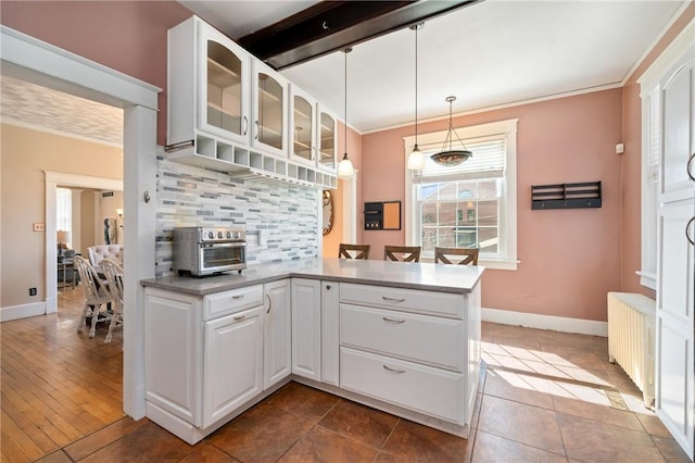 kitchen featuring tasteful backsplash, radiator heating unit, white cabinets, a toaster, and glass insert cabinets