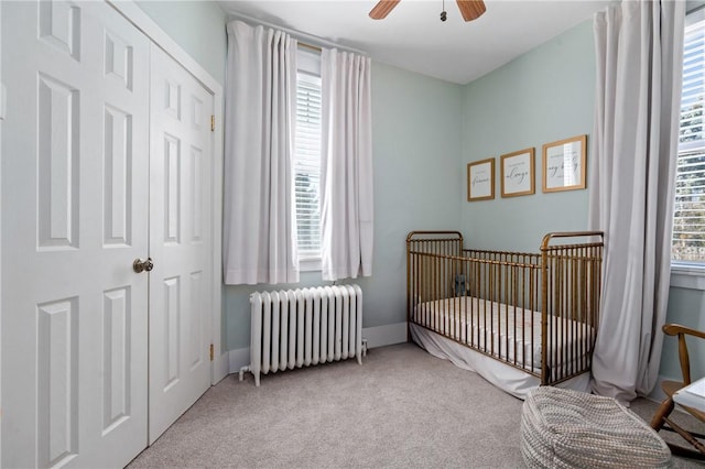 bedroom with a closet, a nursery area, radiator, and carpet