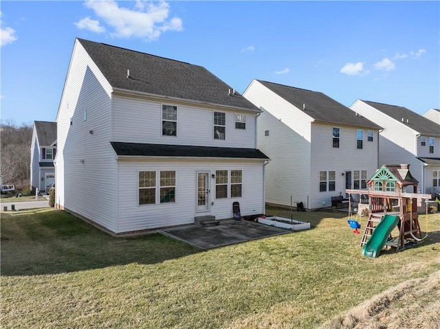 rear view of property with a shingled roof, a playground, entry steps, a lawn, and a patio area