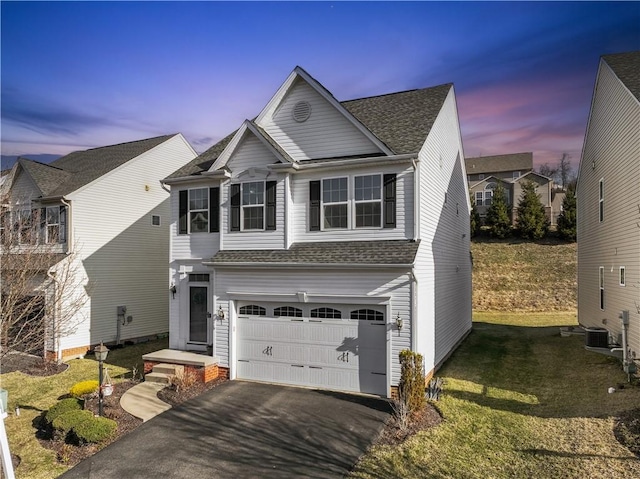 traditional home featuring a front lawn, aphalt driveway, central AC, a shingled roof, and a garage