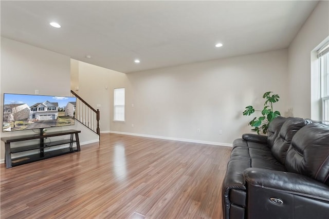 living area featuring recessed lighting, baseboards, light wood-style floors, and stairs