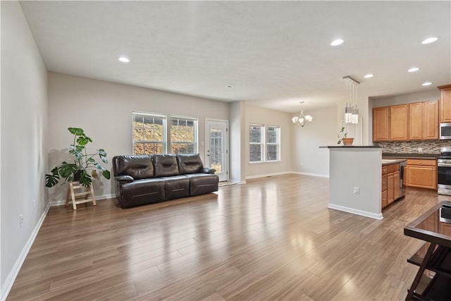 living area with a notable chandelier, recessed lighting, baseboards, and wood finished floors