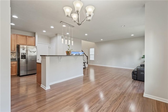 kitchen with dark countertops, open floor plan, decorative backsplash, light wood-style flooring, and stainless steel refrigerator with ice dispenser