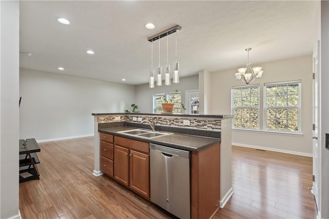 kitchen with dark countertops, dishwasher, light wood-style floors, brown cabinetry, and a sink