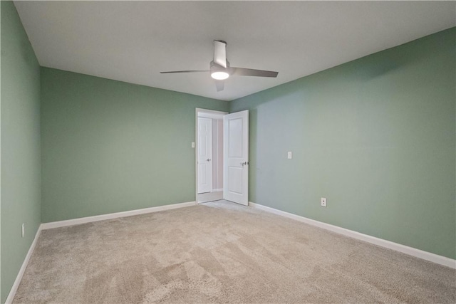 empty room with a ceiling fan, light colored carpet, and baseboards