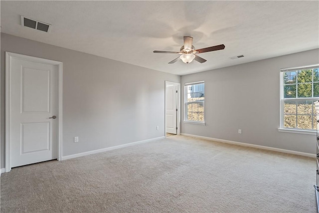 spare room featuring visible vents, light colored carpet, and baseboards