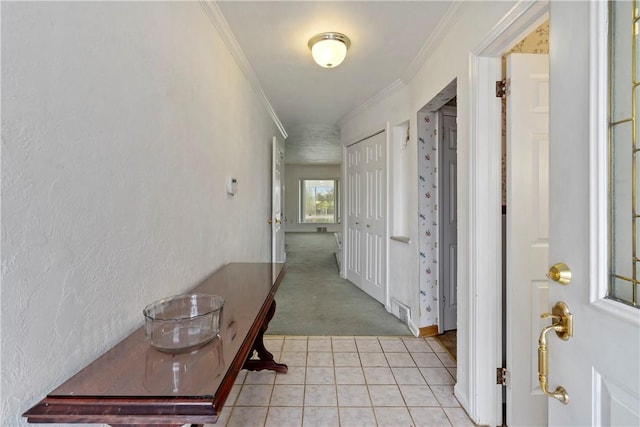 hall with light tile patterned flooring, visible vents, light colored carpet, and ornamental molding