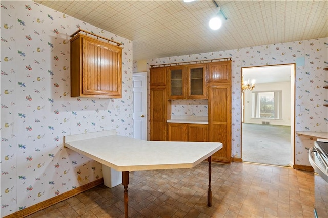 kitchen with wallpapered walls, light countertops, and baseboards