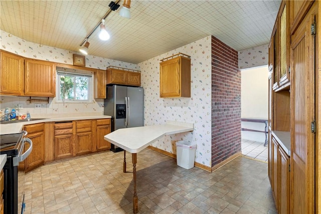 kitchen with brown cabinets, range with electric stovetop, wallpapered walls, and stainless steel fridge with ice dispenser