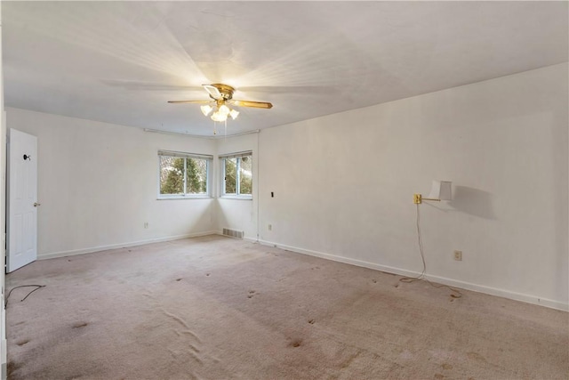 carpeted empty room with visible vents, a ceiling fan, and baseboards