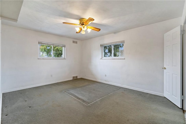 carpeted spare room with visible vents, ceiling fan, and baseboards