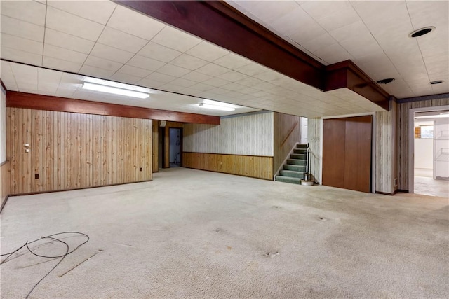 finished basement featuring wood walls, stairs, and carpet floors