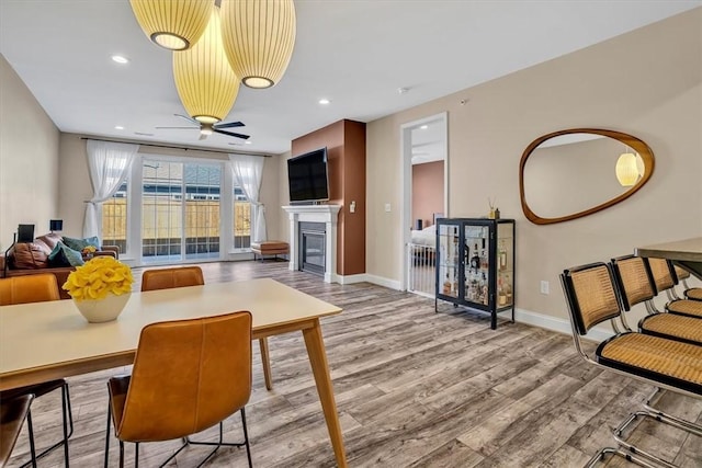 living room featuring a glass covered fireplace, wood finished floors, and baseboards