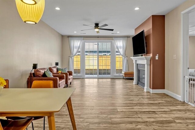 living room with wood finished floors, baseboards, recessed lighting, ceiling fan, and a glass covered fireplace