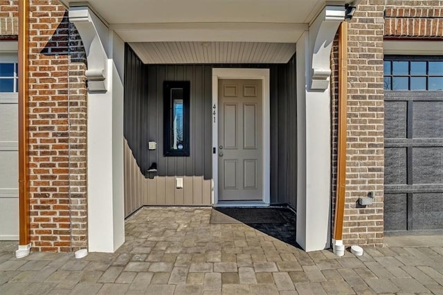 property entrance with a garage and brick siding