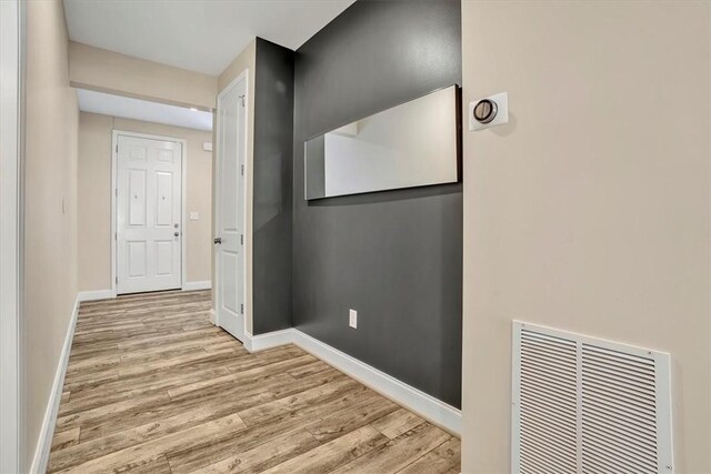 hallway with visible vents, baseboards, and wood finished floors