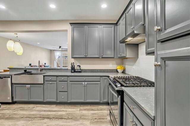 kitchen with a sink, gray cabinetry, stainless steel appliances, under cabinet range hood, and light wood-type flooring