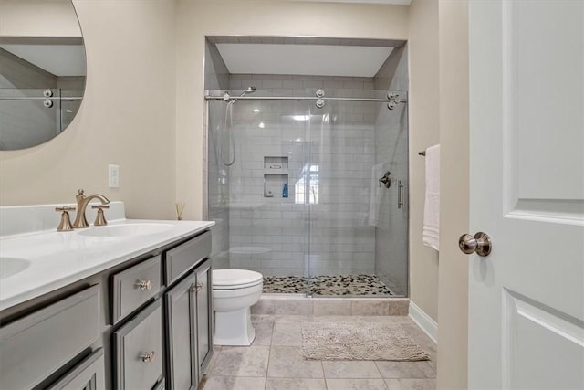 bathroom featuring double vanity, a shower stall, toilet, and a sink