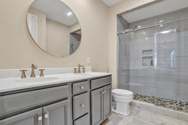 bathroom featuring a sink, toilet, a stall shower, and double vanity