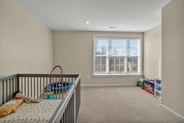 carpeted bedroom featuring a nursery area, baseboards, and visible vents