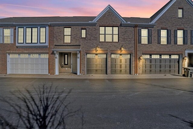 view of property with a garage, brick siding, and driveway