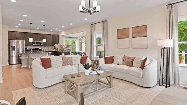 living area with plenty of natural light, light wood-style floors, recessed lighting, and a chandelier