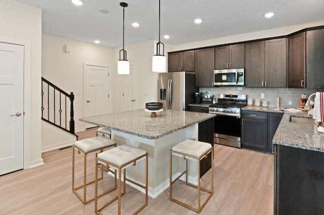 kitchen with a kitchen bar, light wood-style flooring, appliances with stainless steel finishes, and a sink