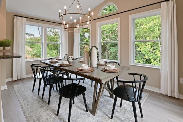 dining room featuring vaulted ceiling, a notable chandelier, light wood-style floors, and baseboards