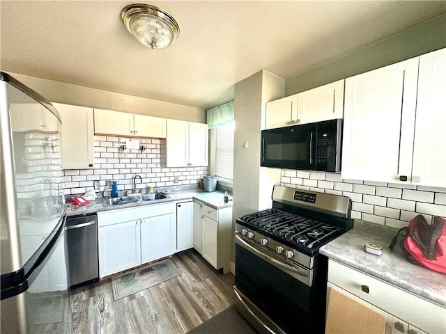 kitchen featuring dark wood-style flooring, white cabinets, appliances with stainless steel finishes, and a sink