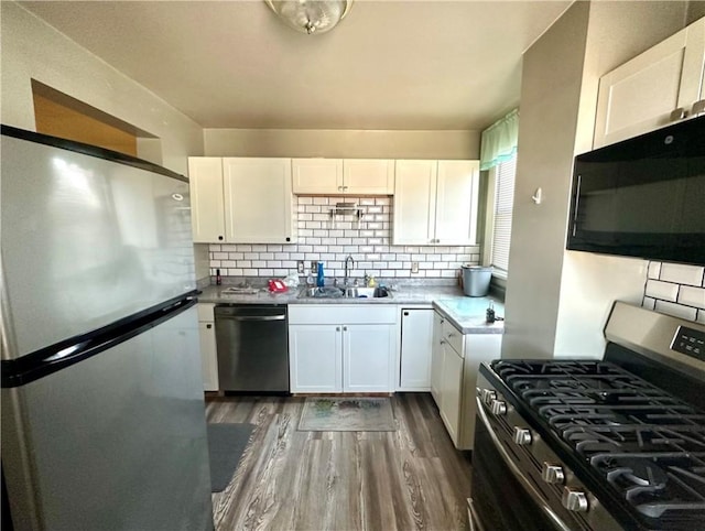 kitchen featuring a sink, dark wood-style floors, white cabinetry, appliances with stainless steel finishes, and decorative backsplash