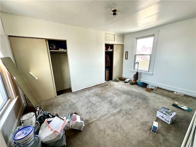 unfurnished bedroom with two closets and baseboards