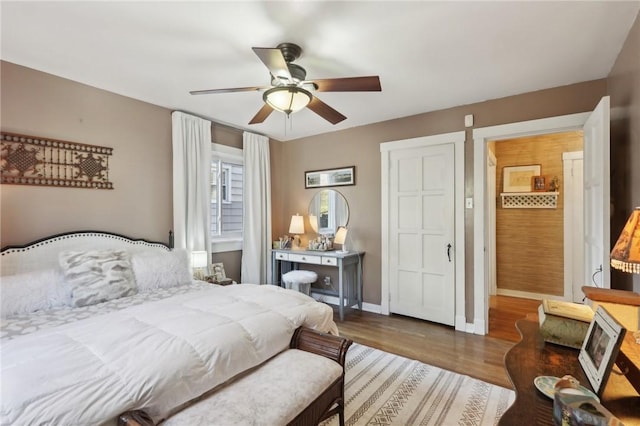 bedroom with ceiling fan, baseboards, and wood finished floors