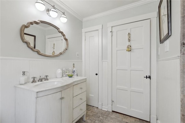 bathroom with vanity, ornamental molding, brick floor, and wainscoting