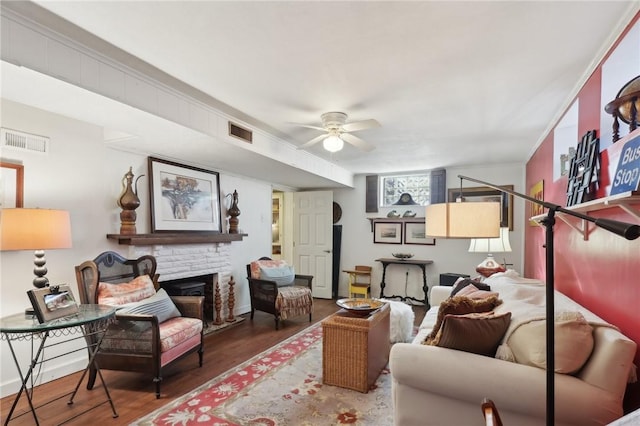 living area featuring visible vents, a fireplace, ceiling fan, and wood finished floors