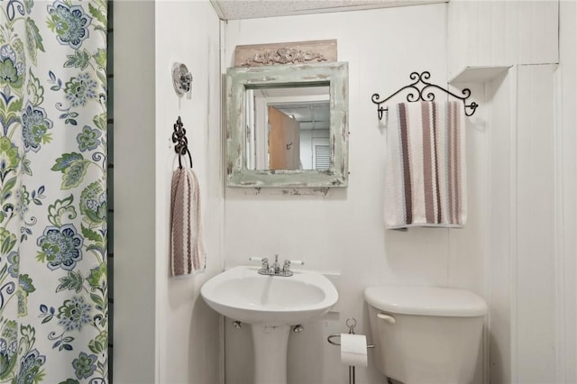 bathroom featuring a sink, a shower with curtain, and toilet