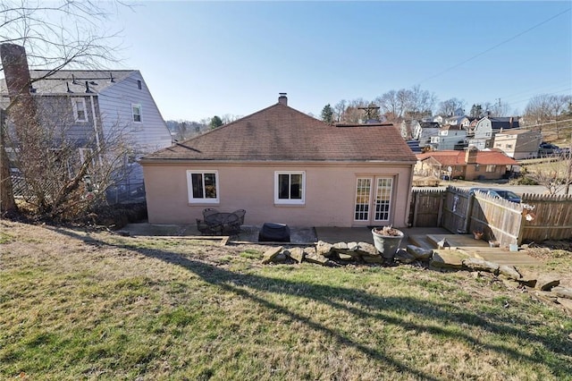 rear view of house with fence, a chimney, french doors, a patio area, and a lawn