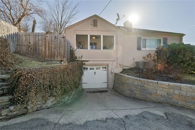 ranch-style house featuring fence, concrete driveway, an attached garage, brick siding, and a chimney