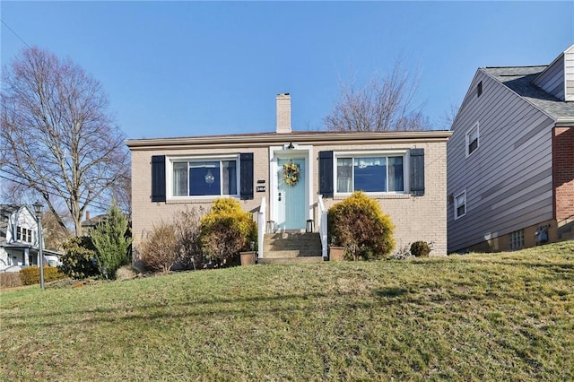 view of front of home featuring brick siding, a chimney, and a front yard