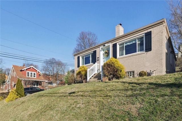 view of front facade with a front lawn, brick siding, and a chimney