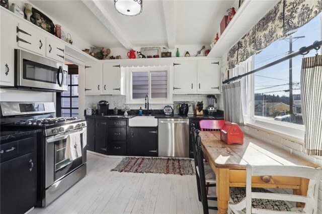 kitchen with white cabinetry, beam ceiling, appliances with stainless steel finishes, and a sink