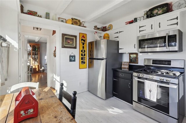 kitchen featuring beam ceiling, white cabinets, and stainless steel appliances