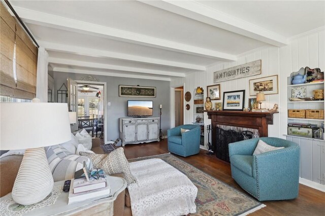 living room featuring beam ceiling, a ceiling fan, wood finished floors, and a fireplace