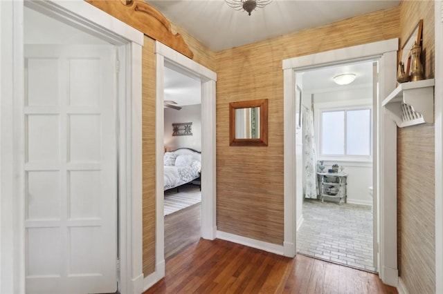 hallway featuring dark wood-type flooring and baseboards